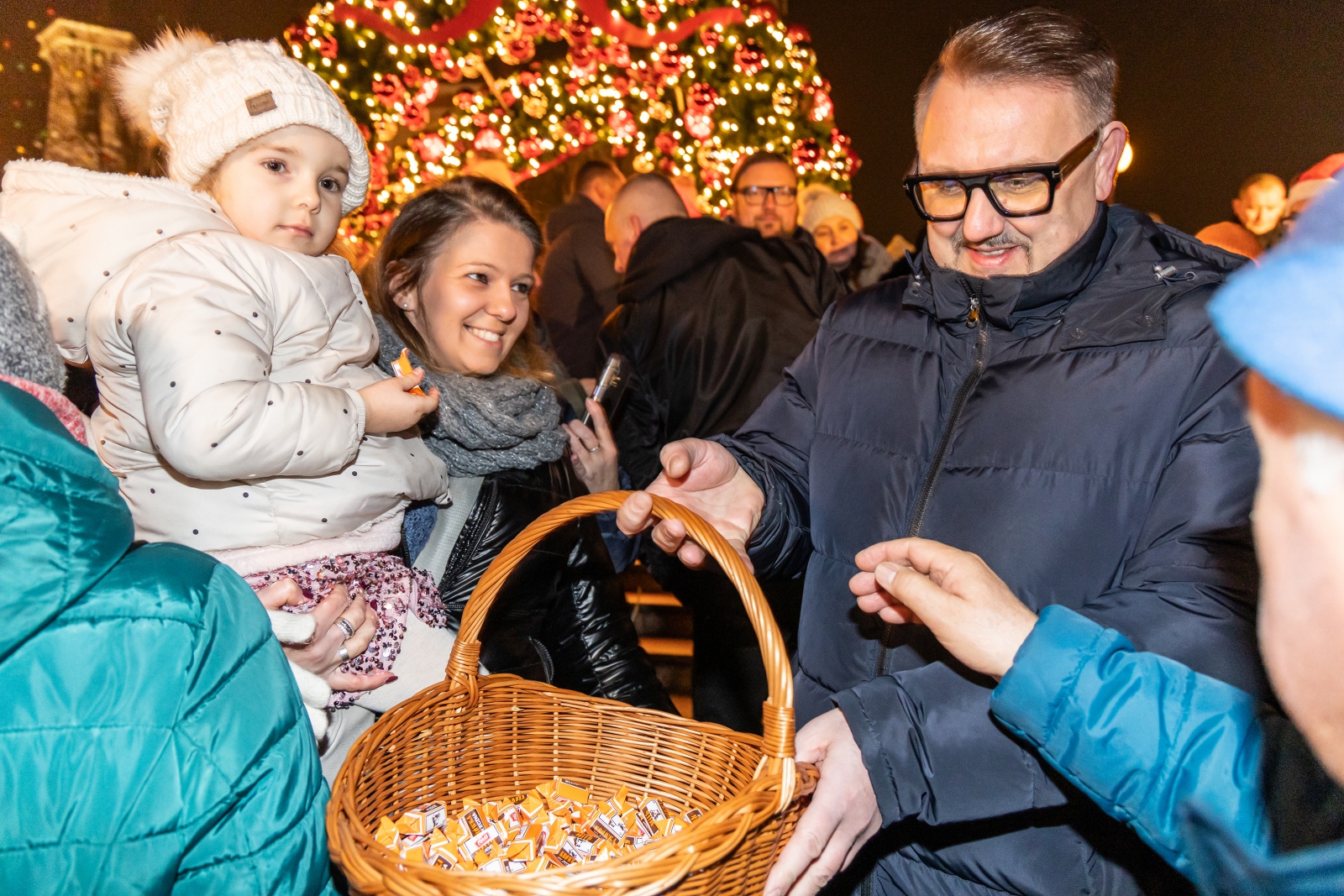 na zdjęciu ozdobione miasto i osoby podczas rozświetlenia