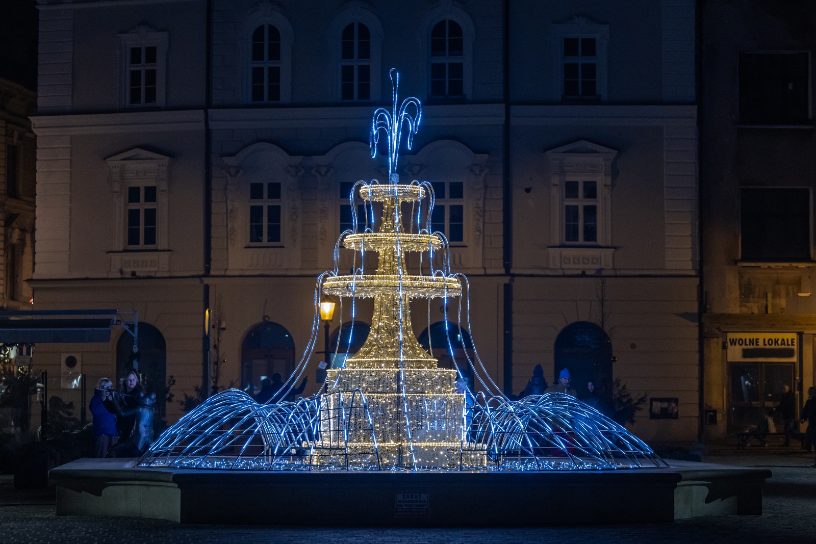 na zdjęciu ozdobione miasto i osoby podczas rozświetlenia
