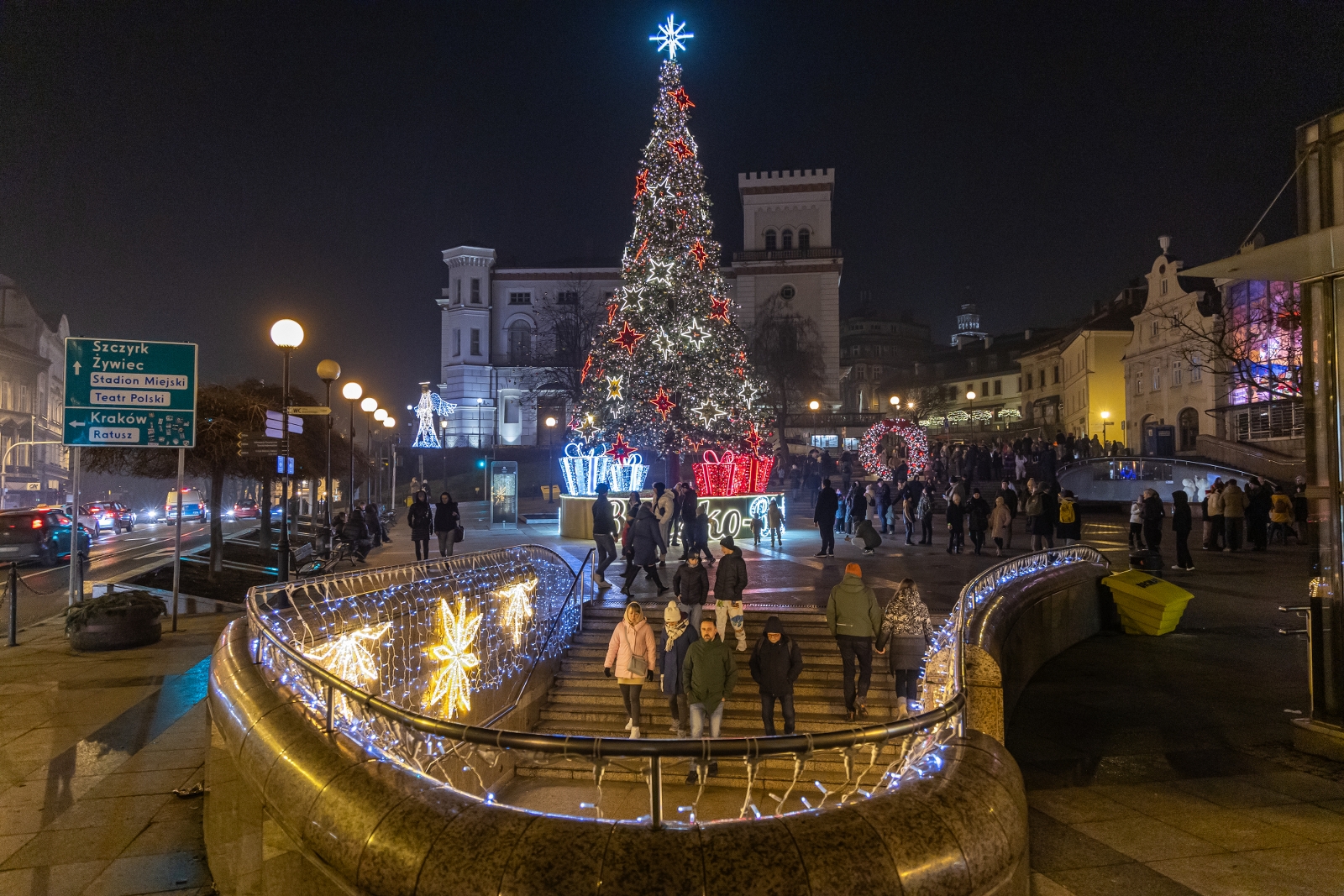 na zdjęciu ozdobione miasto i osoby podczas rozświetlenia