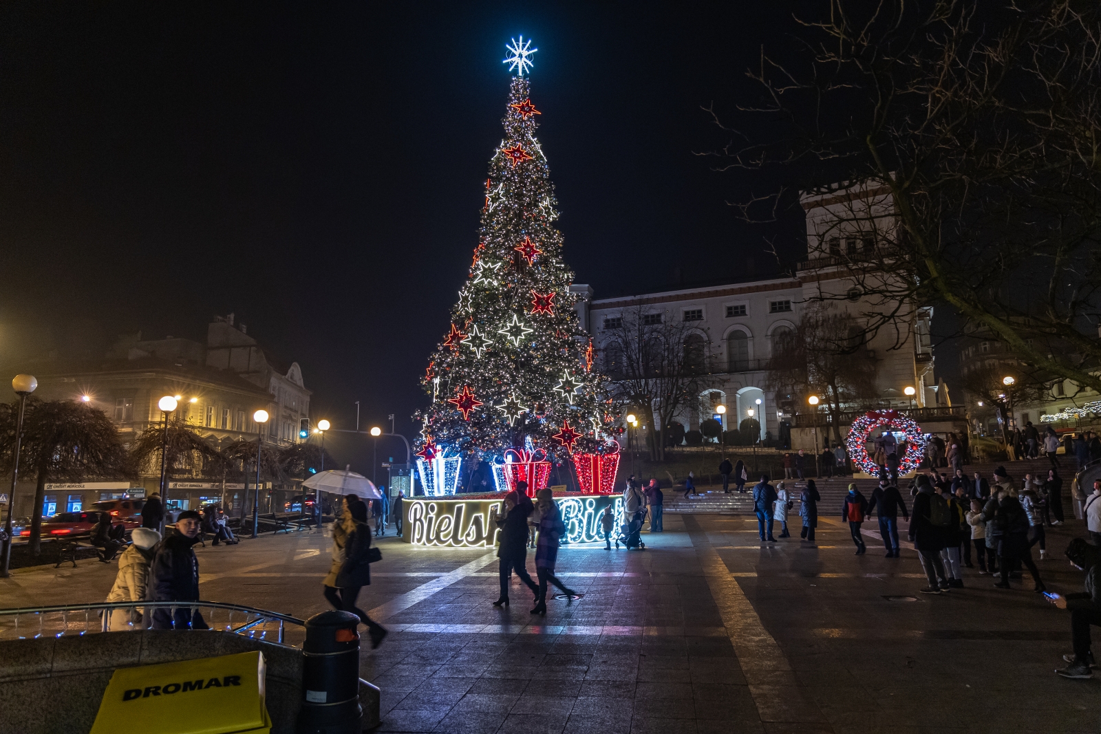 na zdjęciu ozdobione miasto i osoby podczas rozświetlenia