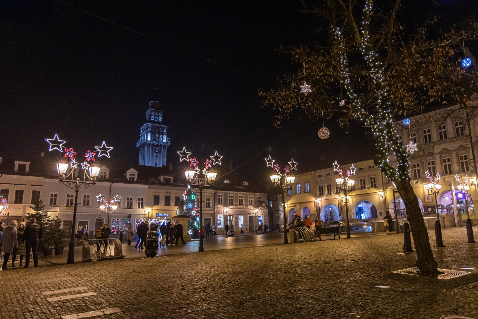 na zdjęciu ozdobione miasto i osoby podczas rozświetlenia