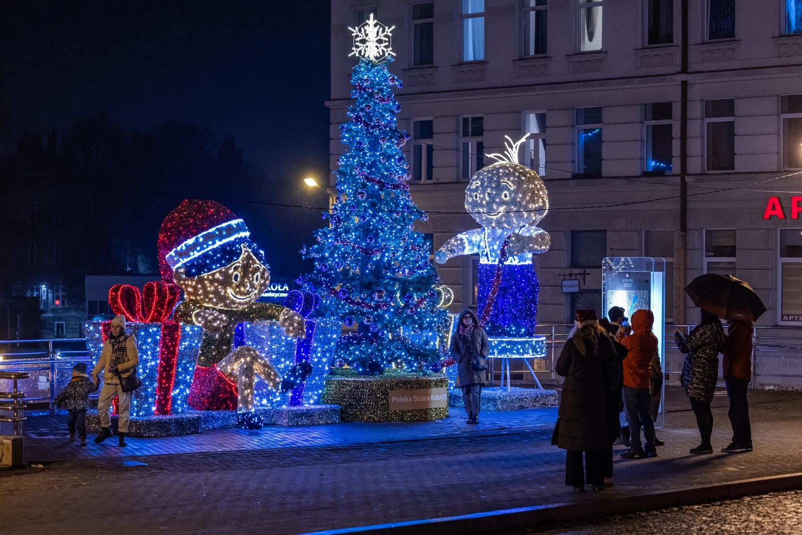 na zdjęciu ozdobione miasto i osoby podczas rozświetlenia