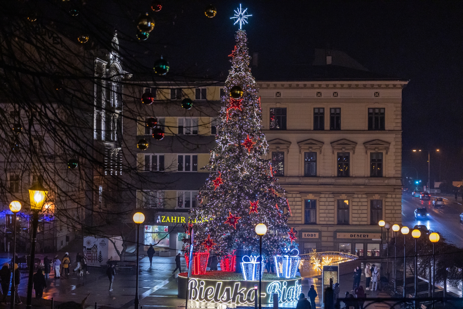 na zdjęciu ozdobione miasto i osoby podczas rozświetlenia