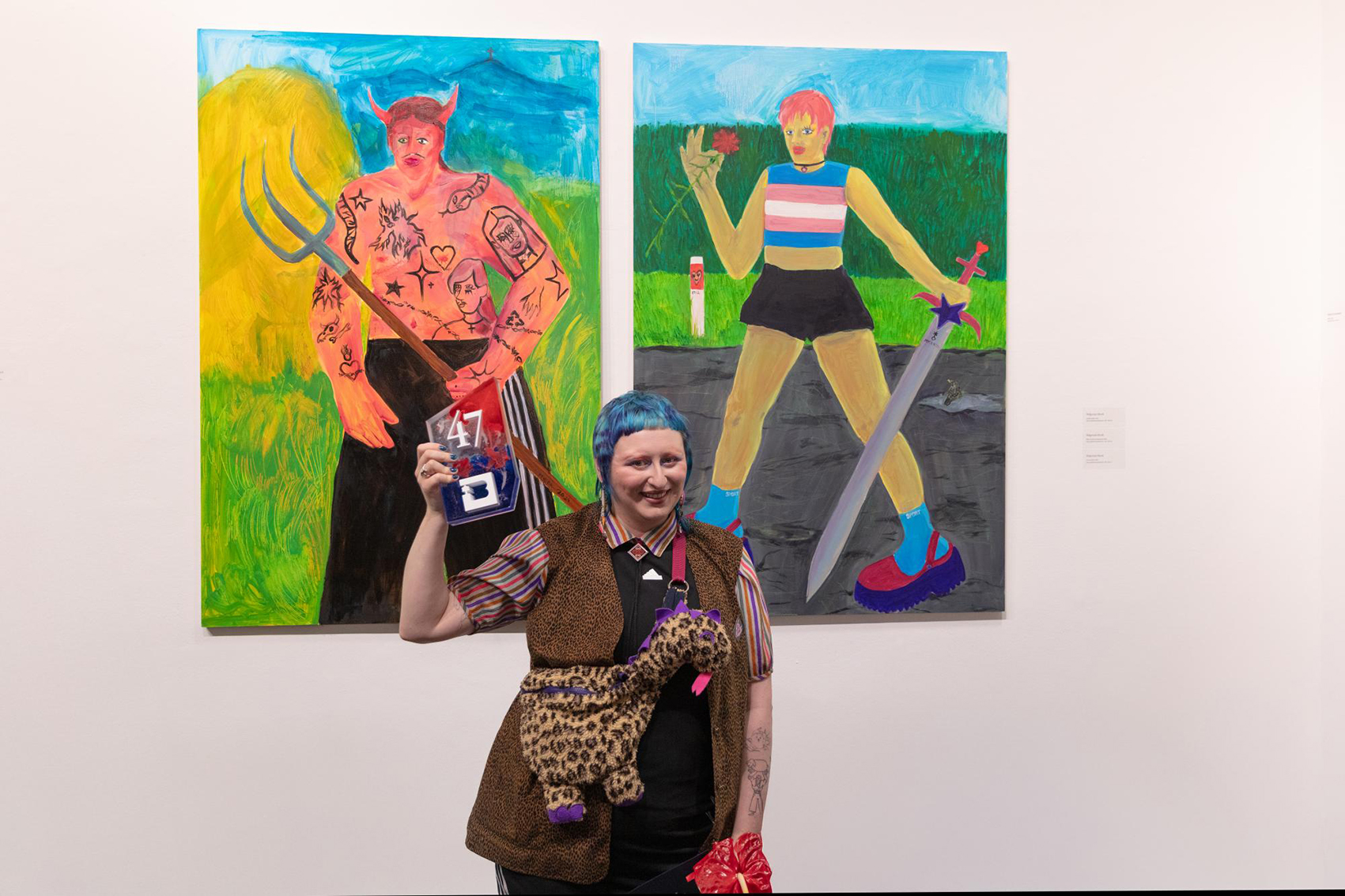 Na zdjęciu osoba nagrodzona przed obrazami