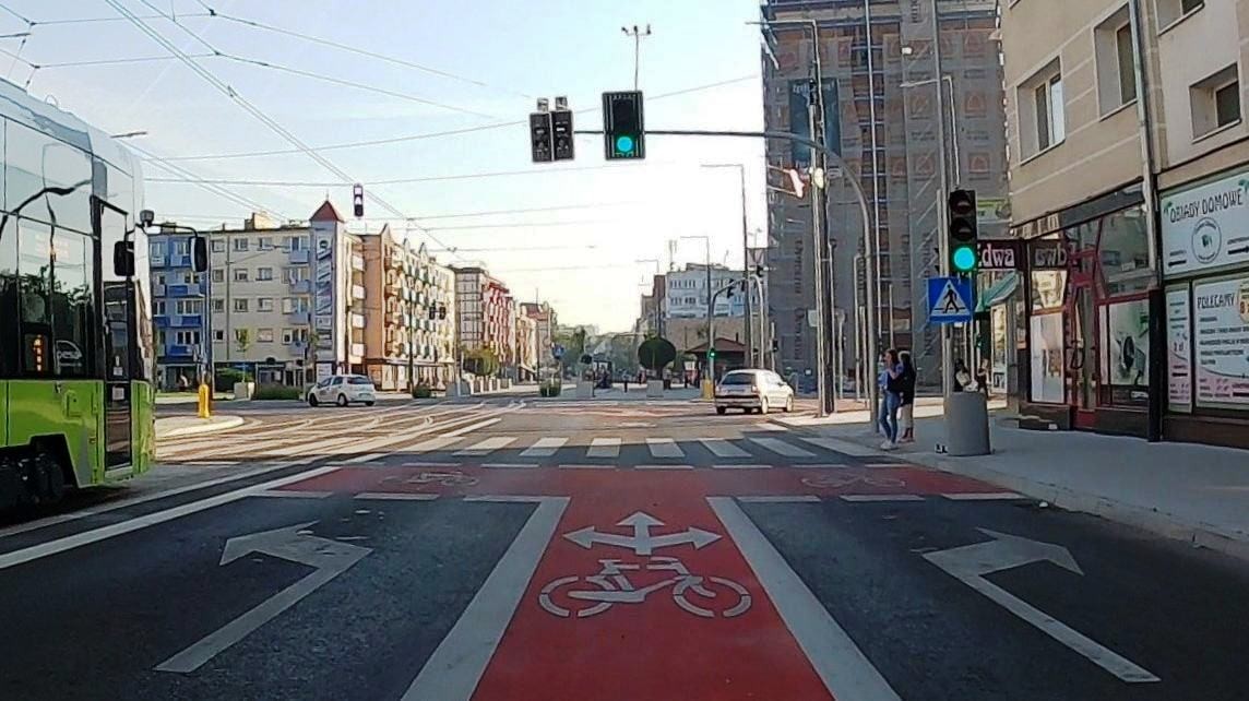 grafika przedstawiająca skrzyżowanie z ulicami, śluzą dla rowerów, przejściem dla pieszych, w otoczeniu budynków 