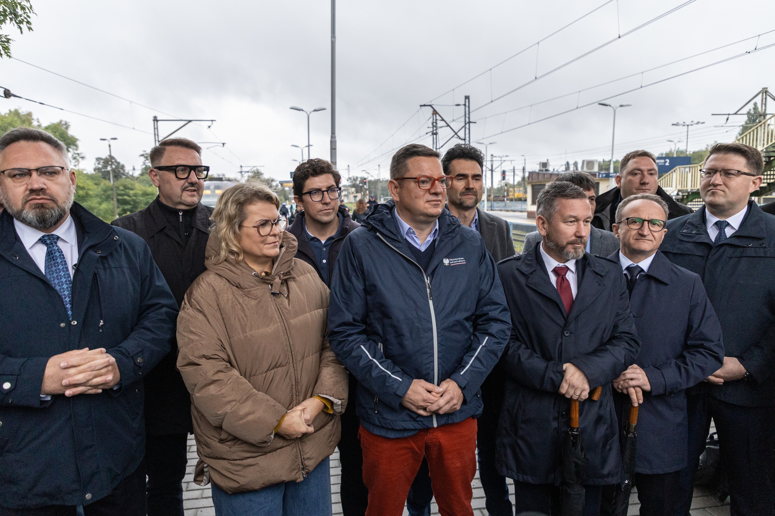 Na zdjęciu stojący ludzie 