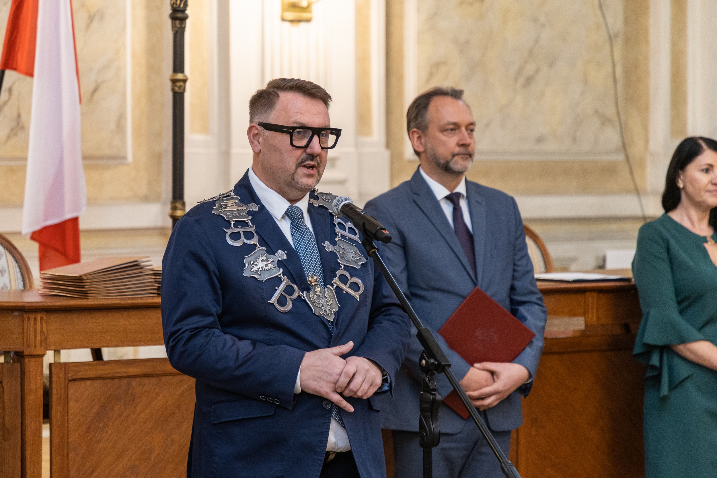 Na zdjęciu stojący ludzie 