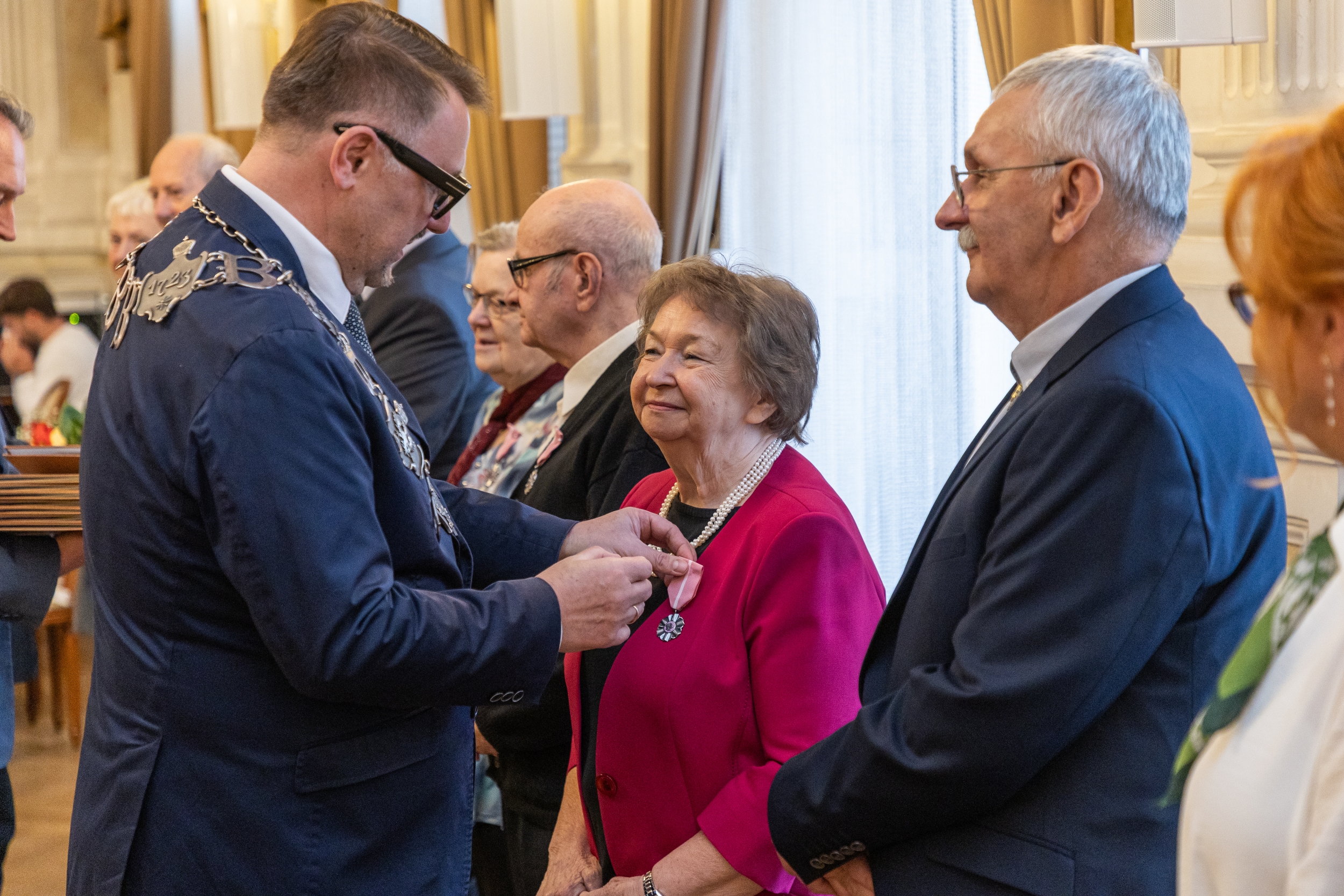 Na zdjęciu stojący ludzie 