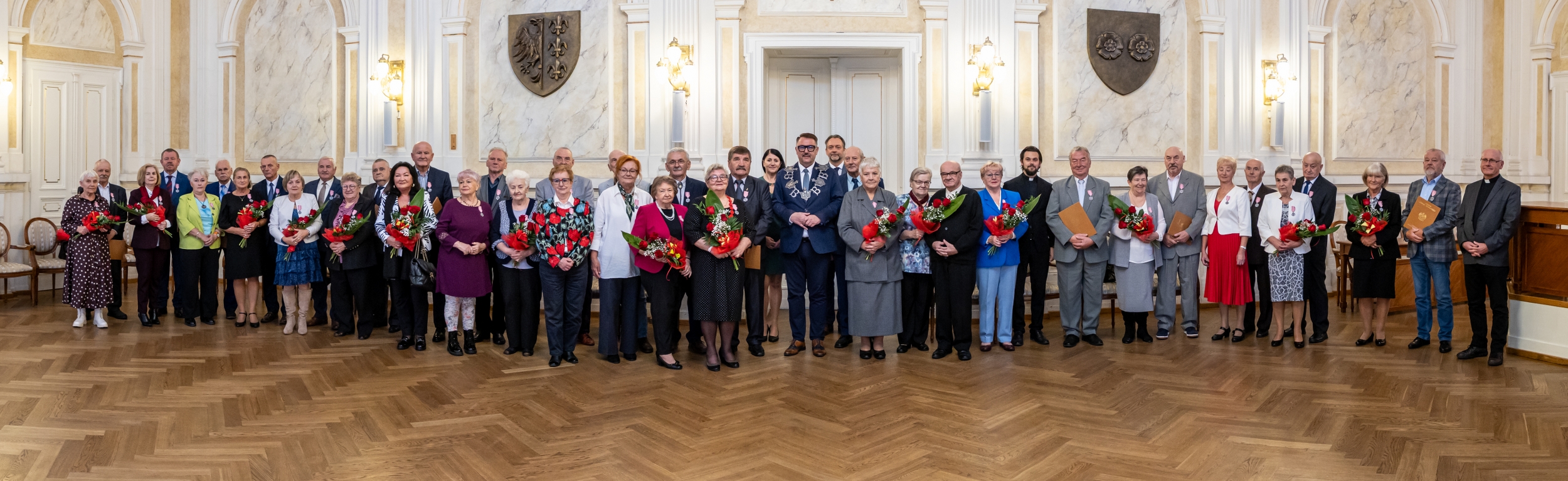 Na zdjęciu stojący ludzie 