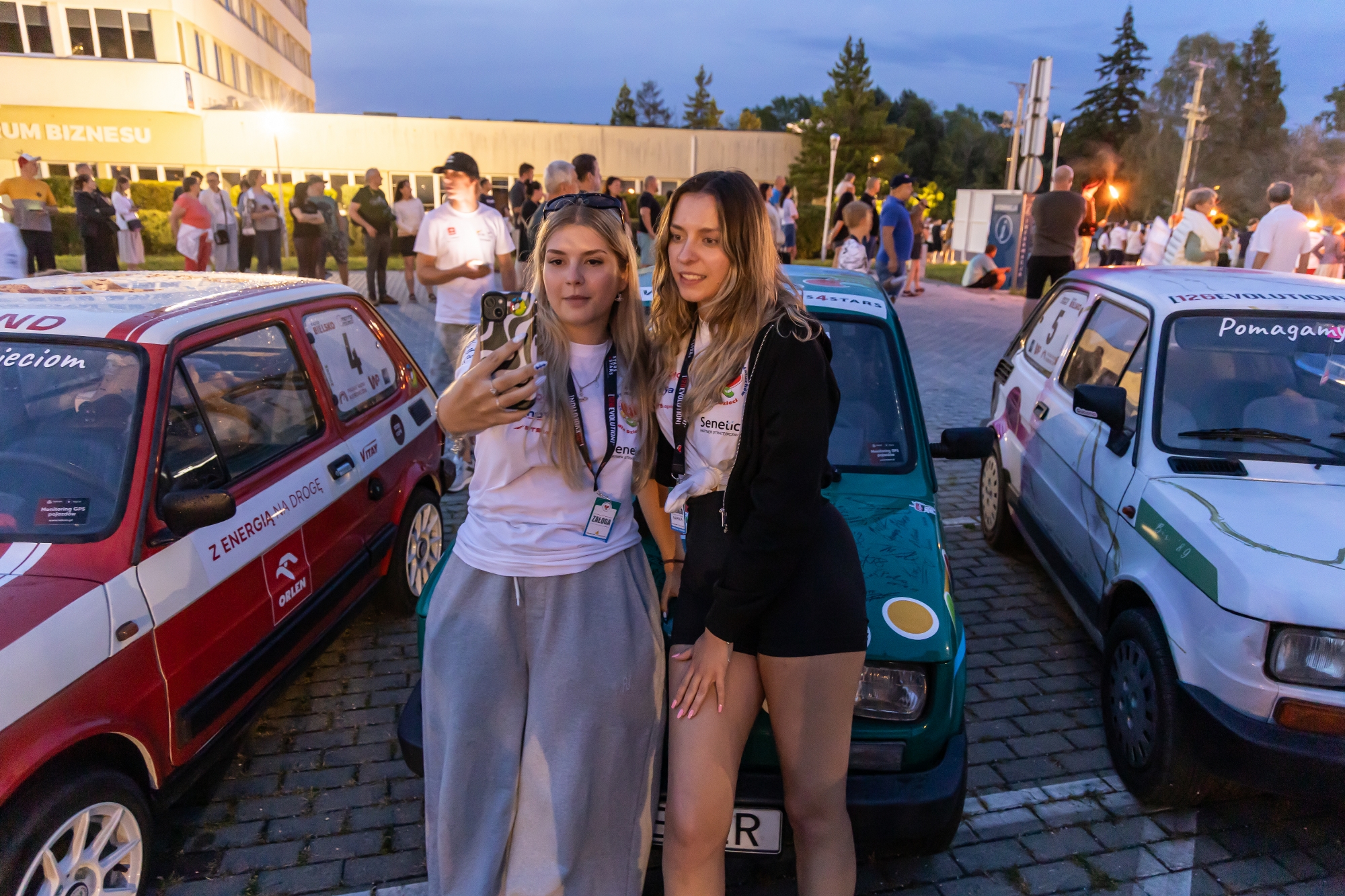 Na zdjęciu dziewczyny na tle maluchów 