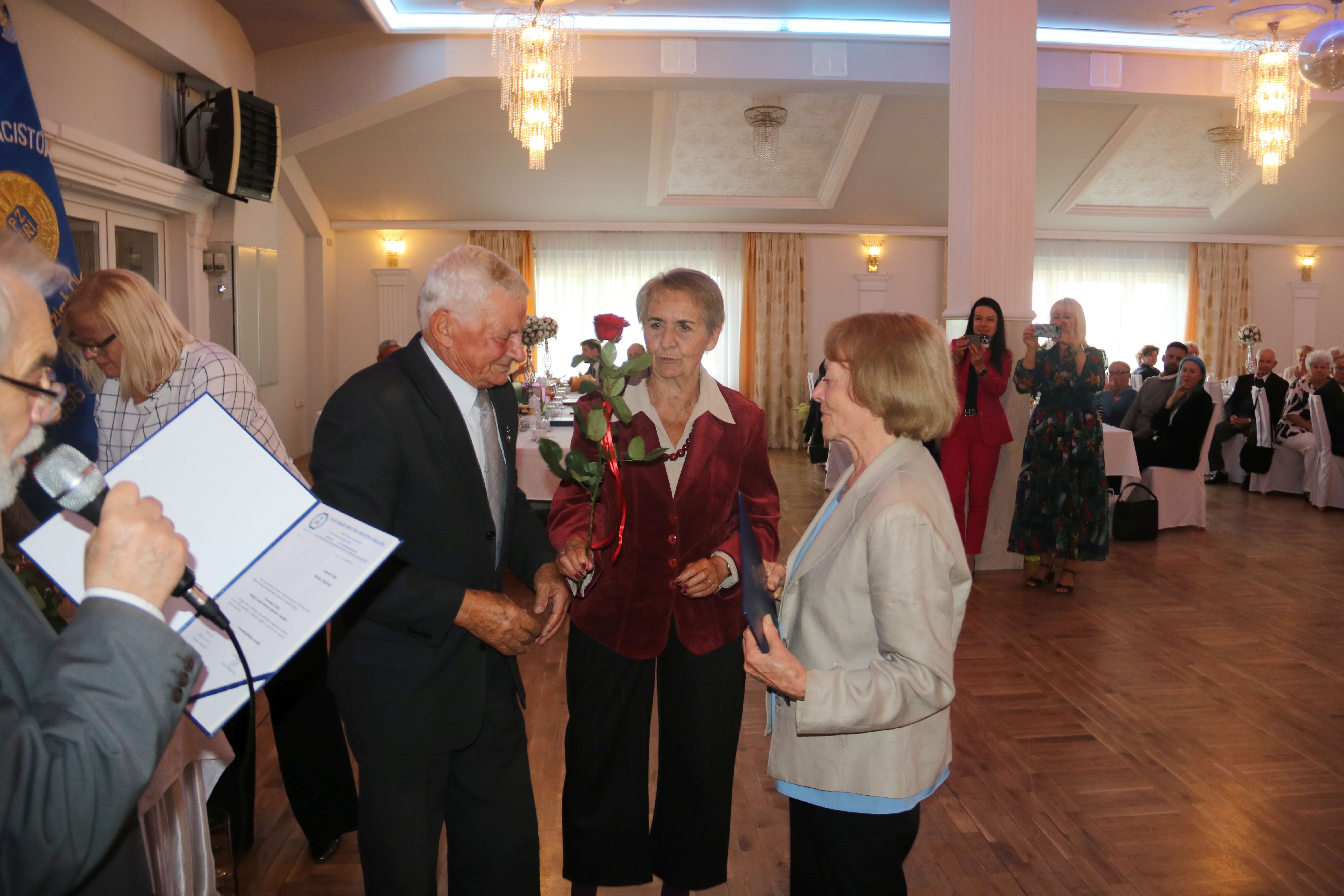 Na zdjęciu stojący ludzie 