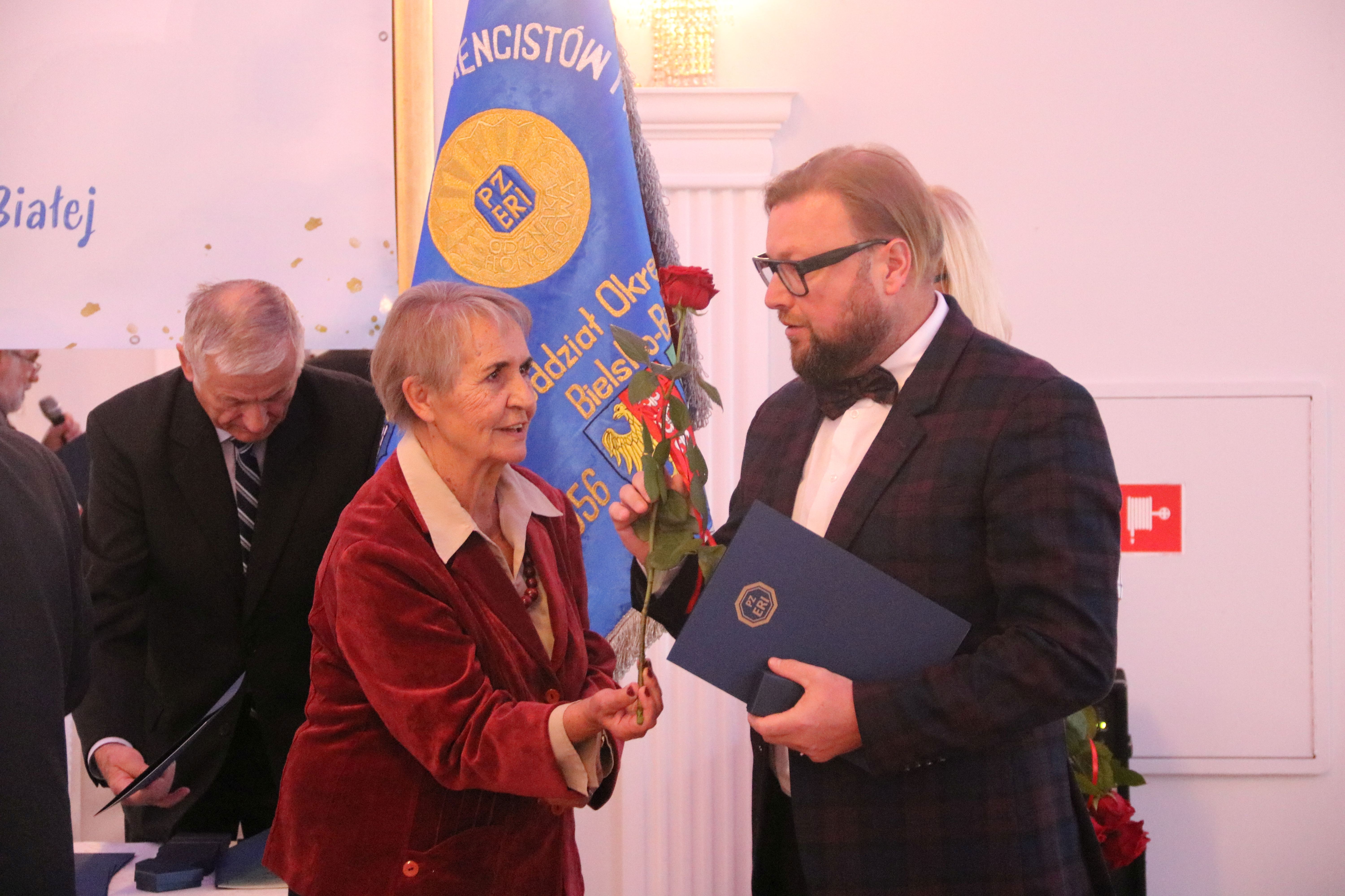 Na zdjęciu stojący ludzie 