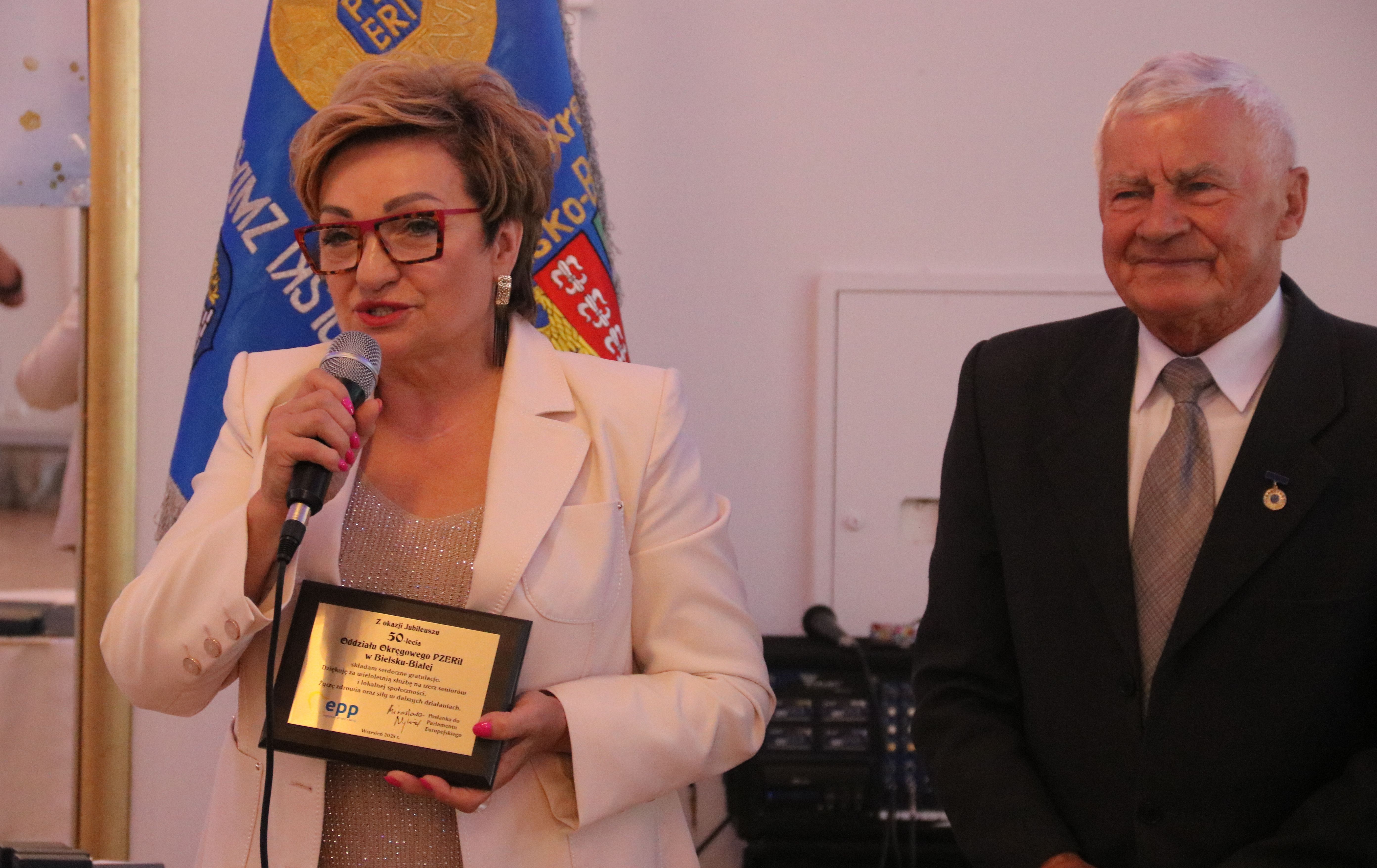Na zdjęciu stojący ludzie 