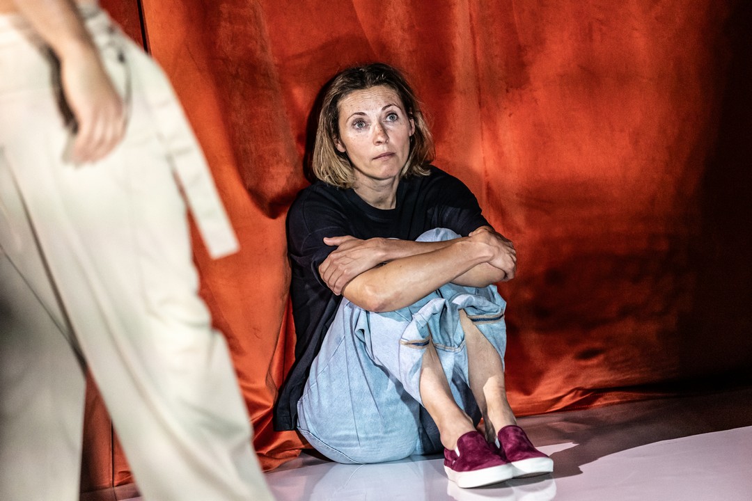 Na zdjęciu smutna dziewczyna siedząca pod ścianą