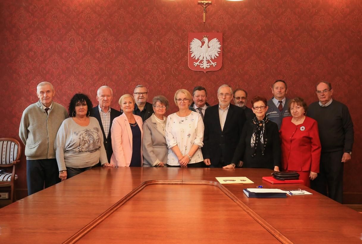 Na zdjęciu stojący ludzie 