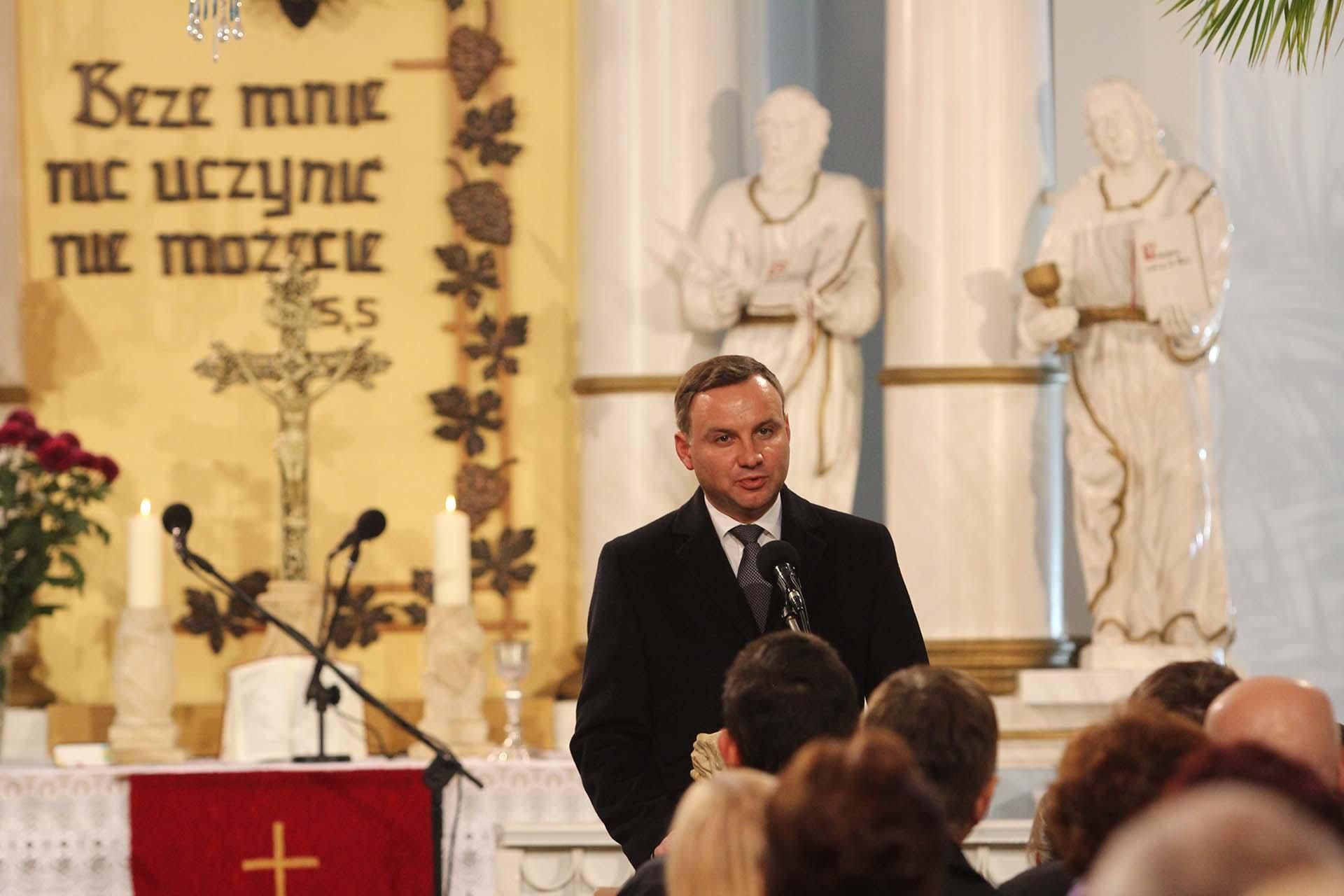 Na zdjęciu stojący ludzie  