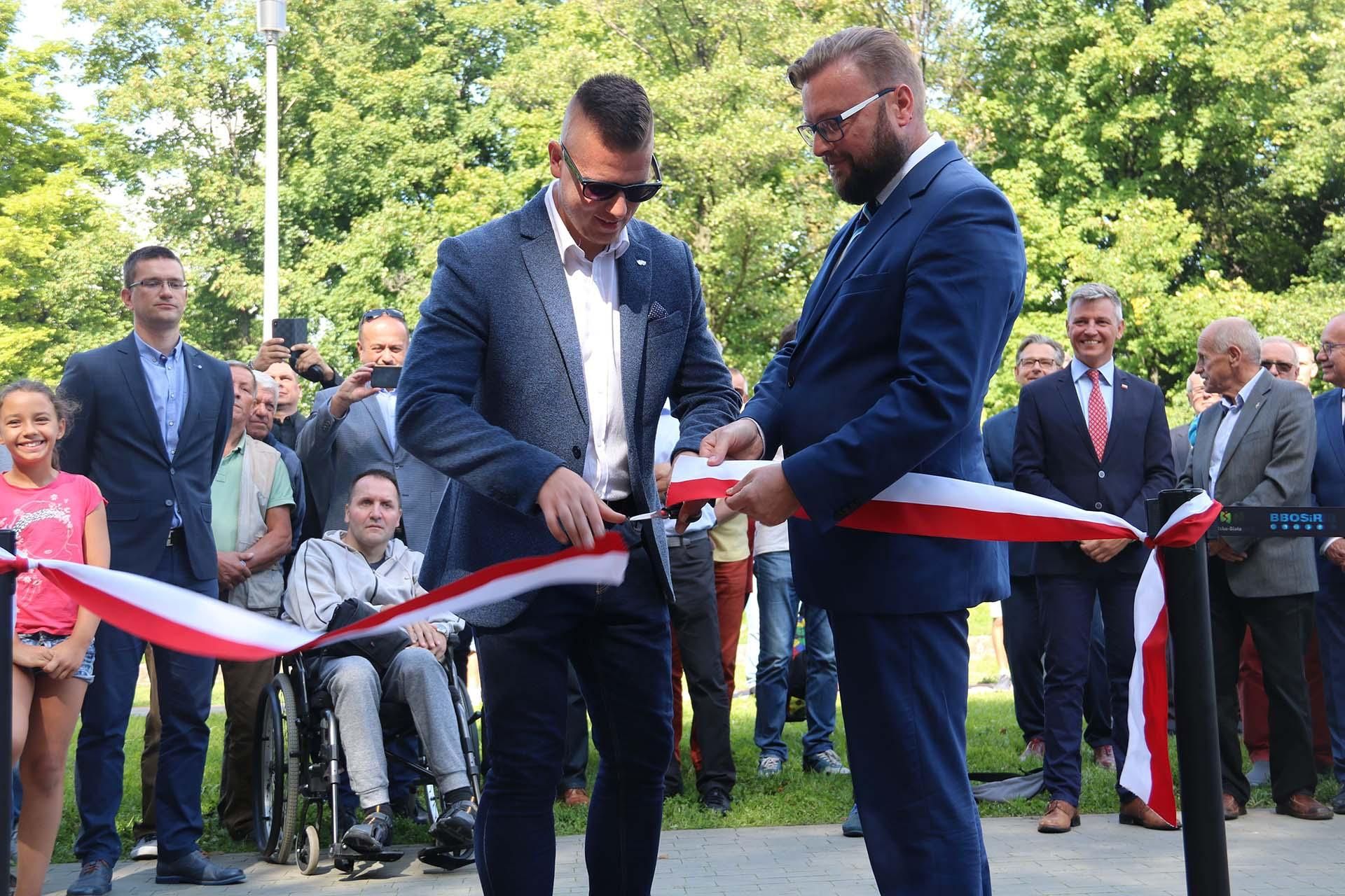 Na zdjęciu stojący ludzie 