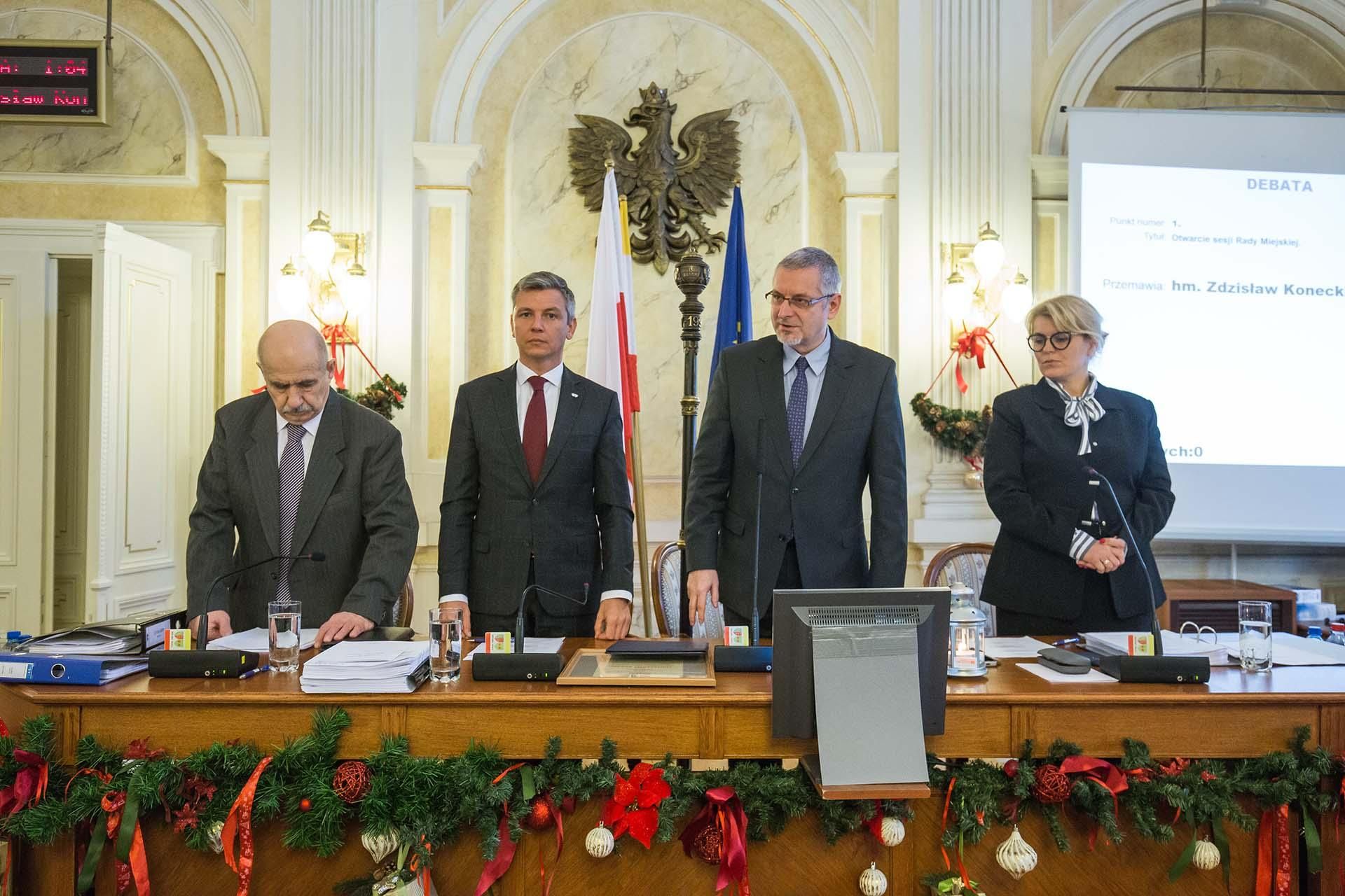 Na zdjęciu stojący ludzie 