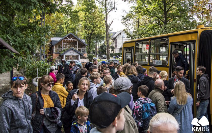 Na zdjęciu stojący ludzie przed autobusem 