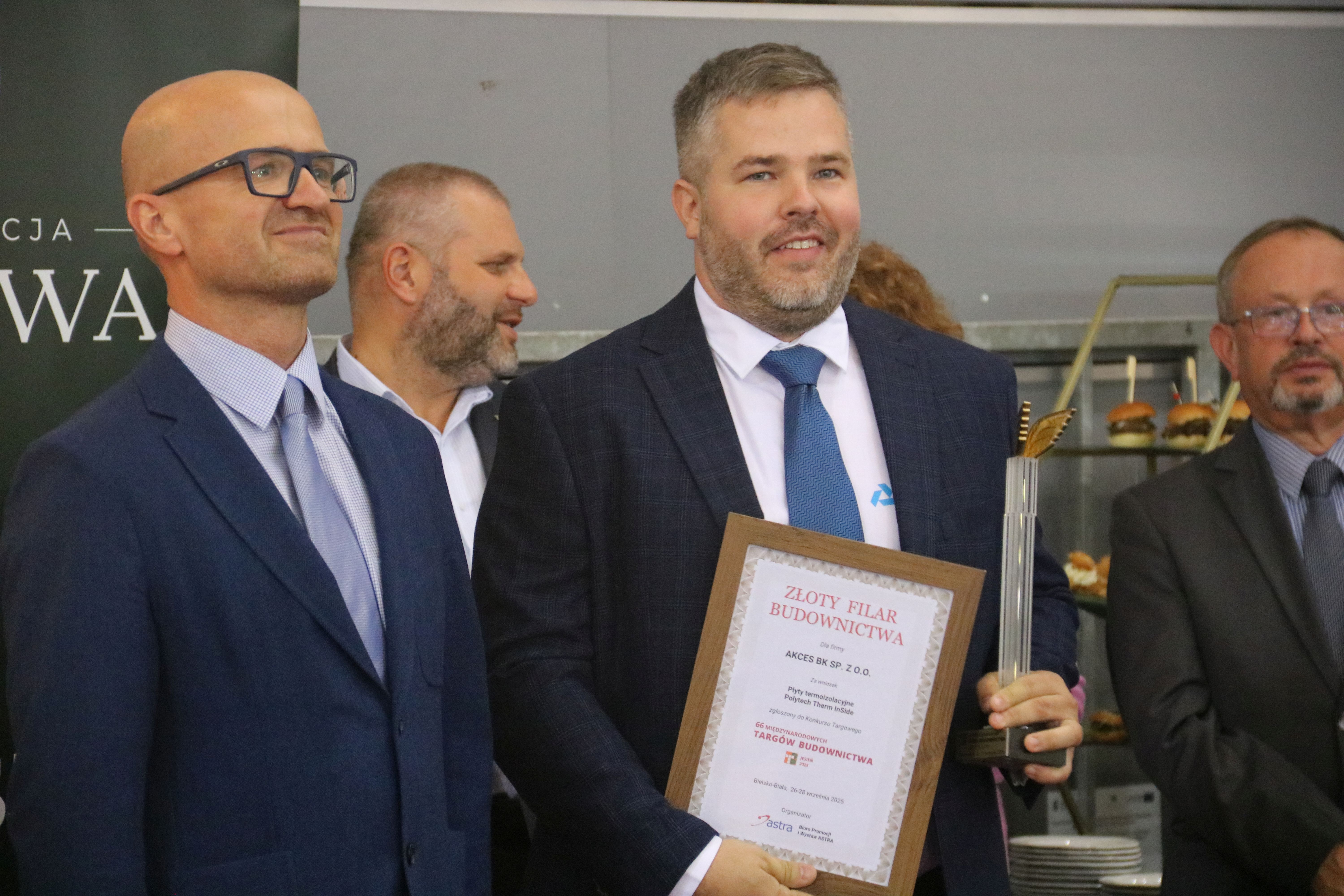 Na zdjęciu stojący ludzie 