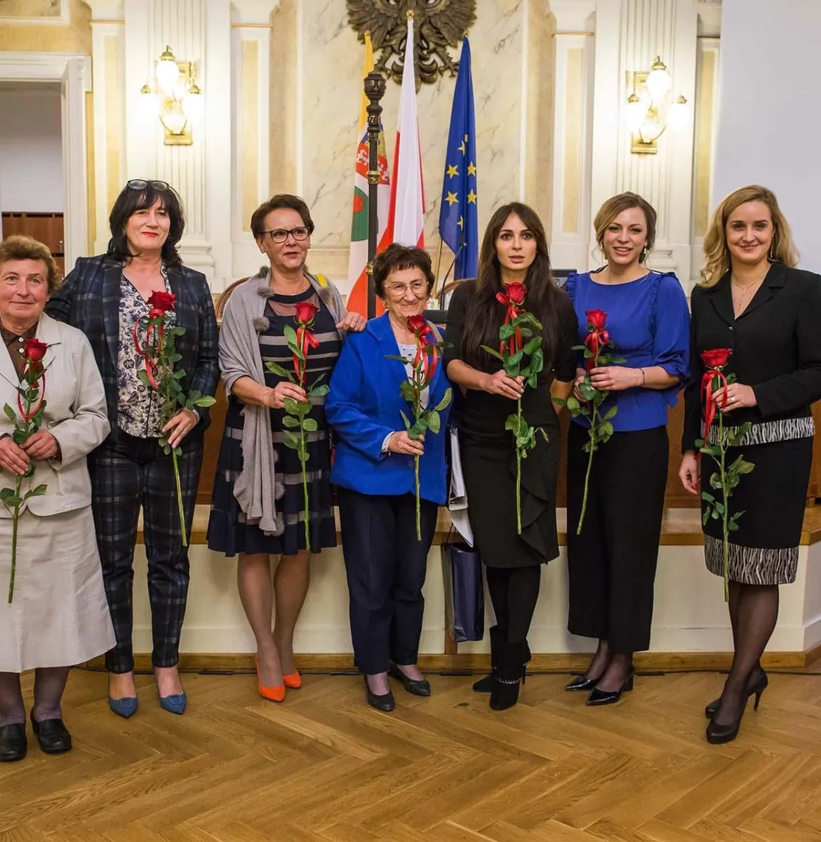 Na zdjęciu stojący ludzie 