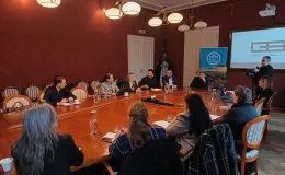 Zdjęcie przedstawiające osoby siedzące przy stole w jednym z pomieszczeń w Ratuszu. 