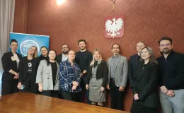 Zdjęcie przedstawiające osoby stojące obok siebie w jednym z pomieszczeń w Ratuszu. 