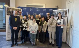 Group posing together inside the Town Hall – standing in front of banners.