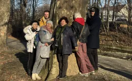 Group of participants smiling and hugging a tree during a shared photograph.