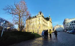Group during a walk in the city square by the Town Hall – listening to the municipal gardener speaking while standing beside a tree decorated with Christmas ornaments.