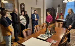 Group of people during a meeting in the Mayor’s office, standing by a table – speaking with the Deputy Mayor of Bielsko-Biała, Adam Ruśniak, and the Head of the Culture and Promotion Department of the Municipal Office in Bielsko-Biała, Przemysław Smyczek.