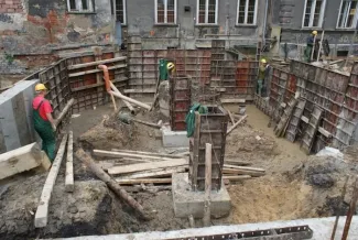 Budowa sali gimnastycznej - na zdjęciu fragment budowy, pracownicy oraz budynek w tle