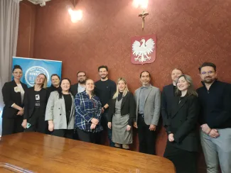 Zdjęcie przedstawiające osoby stojące obok siebie w jednym z pomieszczeń w Ratuszu. 