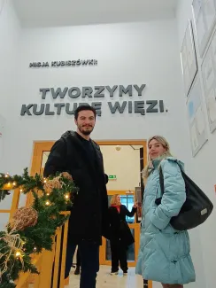 Zdjęcie przedstawiające dwie osoby stojące przed wejściem do pomieszczenia.