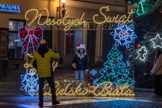 na zdjęciu ozdobione miasto i osoby podczas rozświetlenia
