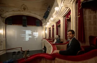 Na zdjęciu wnętrze widowni teatru, mężczyzna siedzący w loży