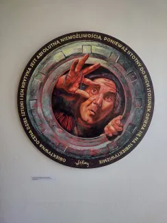 Na zdjęciu okrągła praca plastyczna przedstawiająca człowieka próbującego się wydostać