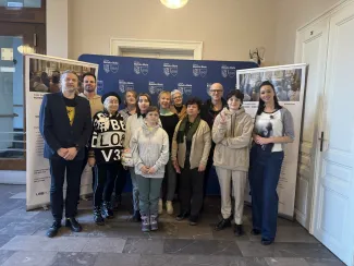 Group posing together inside the Town Hall – standing in front of banners.