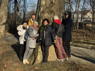 Group of participants smiling and hugging a tree during a shared photograph.