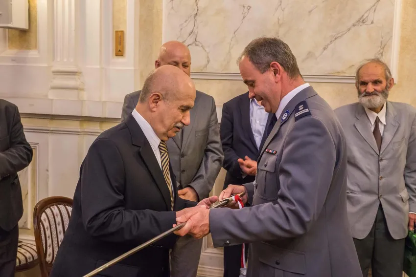 Na zdjęciu stojący ludzie 