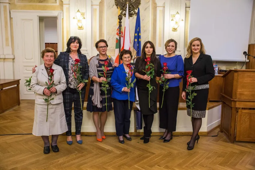 Na zdjęciu stojący ludzie 