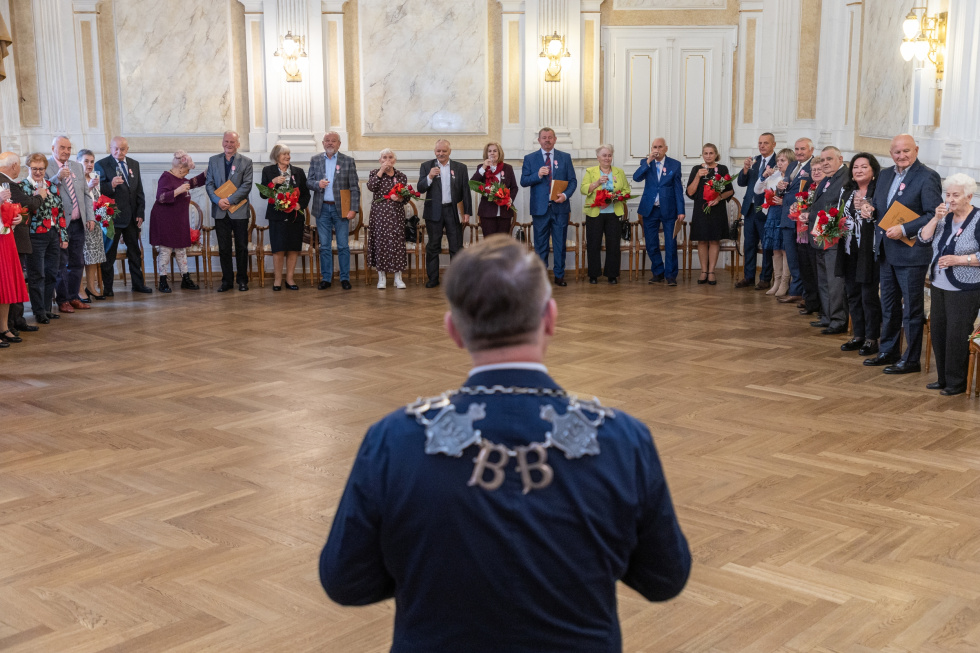 Na zdjęciu stojący ludzie 