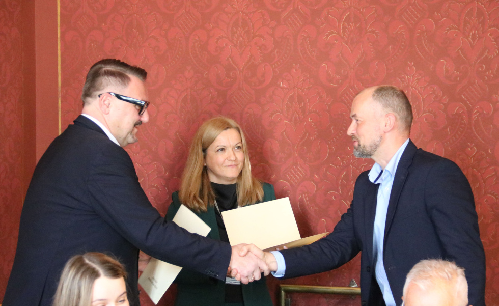 Na zdjęciu stojący ludzie 