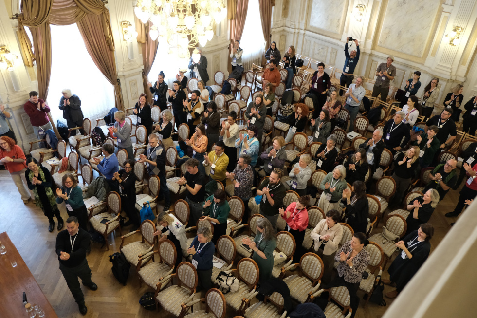 Na zdjęciu stojący ludzie 