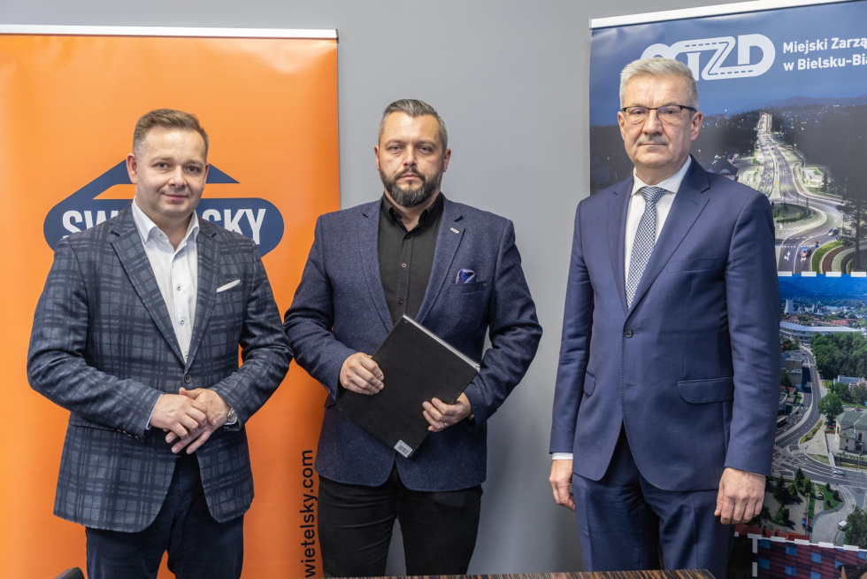 Na zdjęciu stojący ludzie 