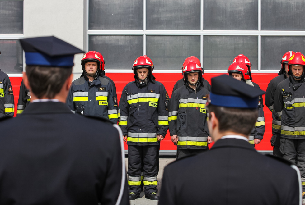 Na zdjęciu stojący ludzie 
