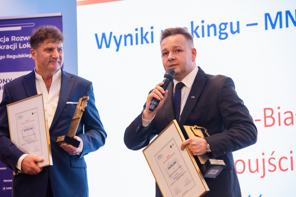 Na zdjęciu stojący ludzie 