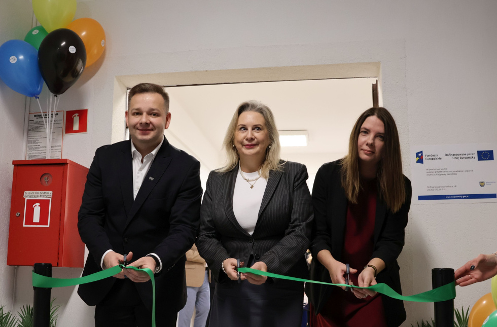 Na zdjęciu stojący ludzie 