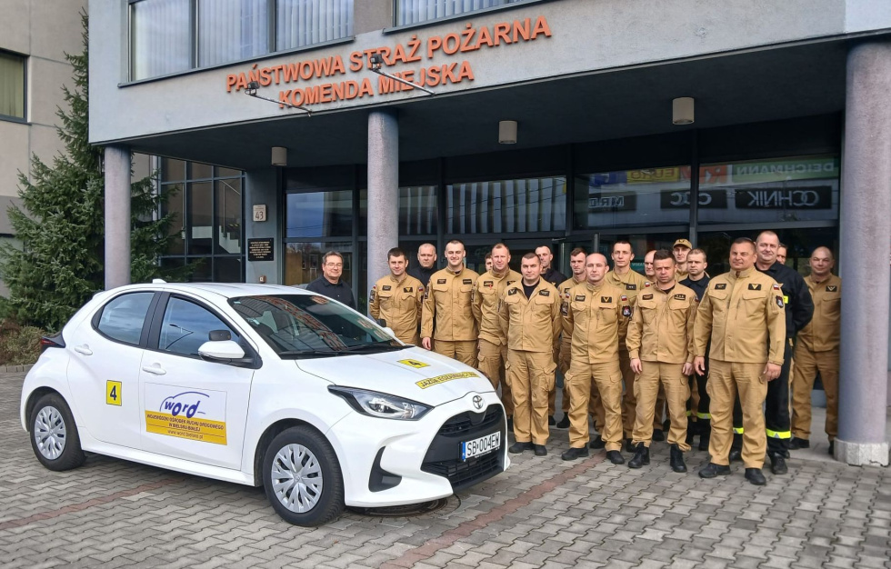 Na zdjęciu stojący ludzie 