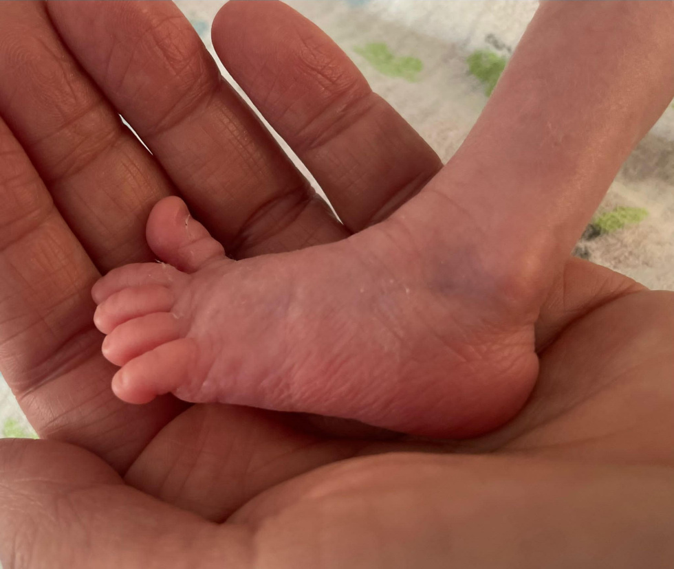 na zdjęciu stópka wcześniaka na dłoni dorosłej osoby